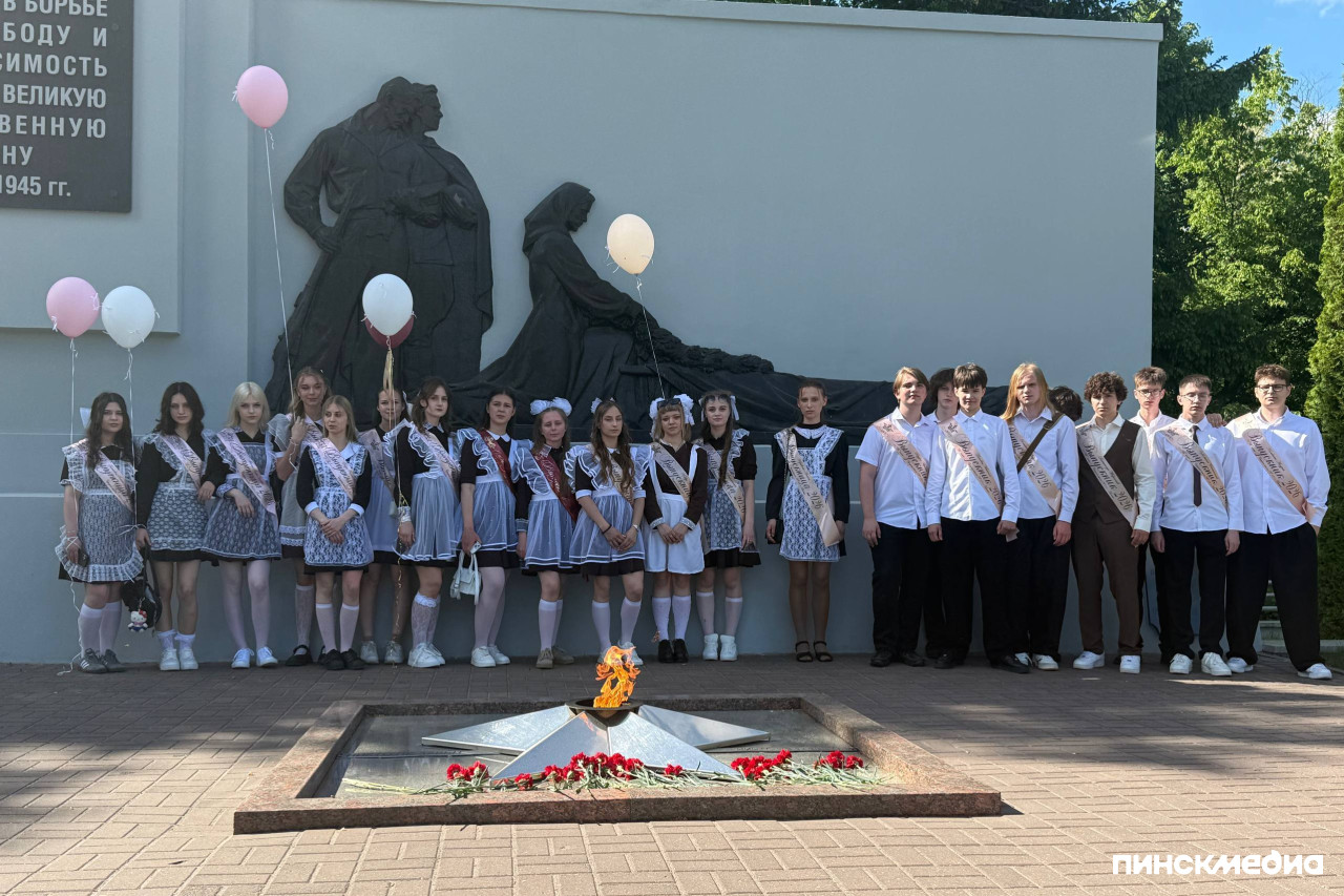 Выпускники СШ 18 города Пинска стоят на общем фото возле Мемориального комплекса освободителям в парке.
