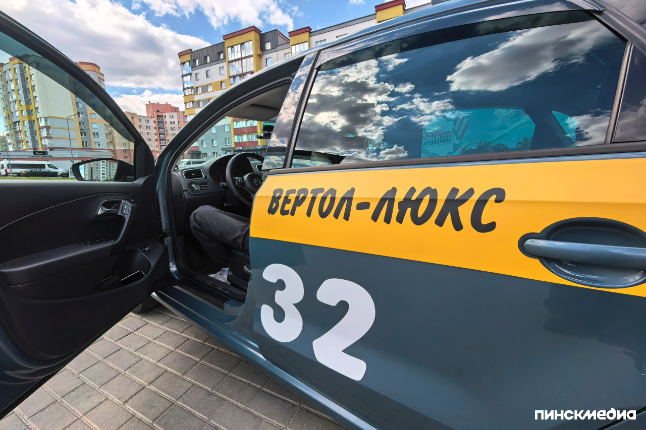 Водитель такси Вертол-Люкс в опрятной одежде за рулем автомобиля